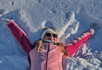 Portrait of mature woman having fun lying in snow