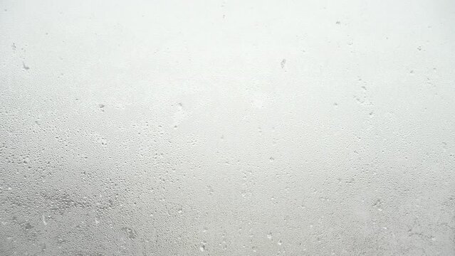 窓ガラスに打ち付ける雪の氷