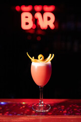 Beautiful red cocktail on the bar counter in a nightclub, bar. Garnished with orange zest