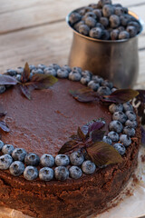 chocolate cheesecake with blueberries and basil on wood background