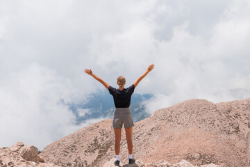 The girl stands on the edge of a high mountain in the clouds. The girl looks at the beautiful mountain landscape Antalya Turkey