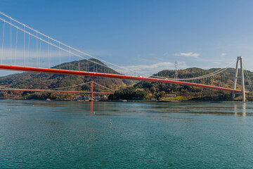 Suspension bridges over large body of water with mountains in background.