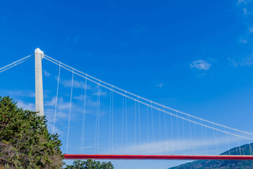 Pylons of suspension bridge on highway under blue sky.