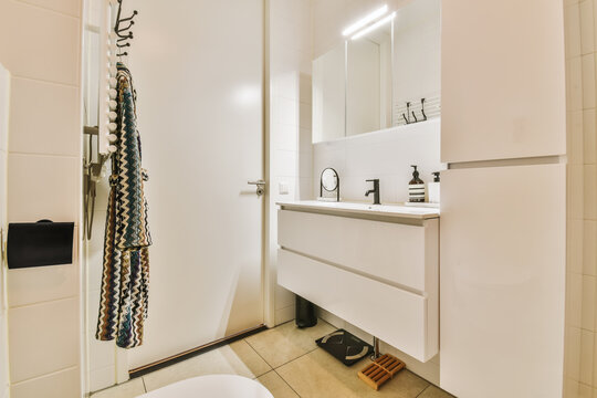 A Bathroom With A Toilet, Mirror And Towel Hanging On The Wall Behind It Is A White Door That Leads To An Open Shower