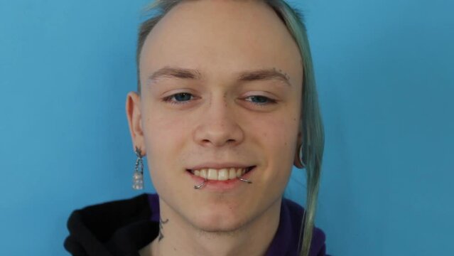 a large portrait of an lgbt guy smiling on a blue isolated background.