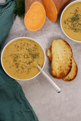 sweet potato puree soup in white bowl with garlic bread on grey marble table