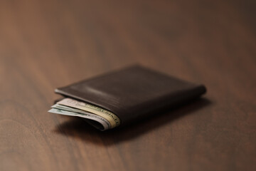 Bespoke brown all leather wallet on walnut table with cash