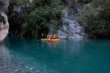 Fototapeta na wymiar Group of tourists on a rafting boat in Göynük Canyon.Tourists and guide on an inflatable boat rafting down the blue water.