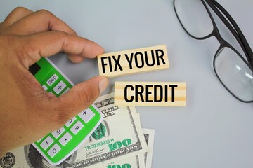 paper money, calculator and glasses with the words fix your credit. Credit repair is the act of...