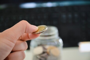 person putting coin into a glass jar