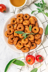 Vegetable italian snacks taralli or tarallini with  ingredients tomatoes,  sage leaves in plate and olive oil in bowl, top view