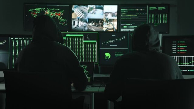 Team of unrecognizable Computer hackers coding and using monitor screens to program security breach