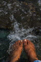 POV of a male bare feet in mountain river water for relaxing.