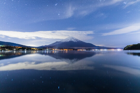 冬の山中湖の水面に映る富士山と星空