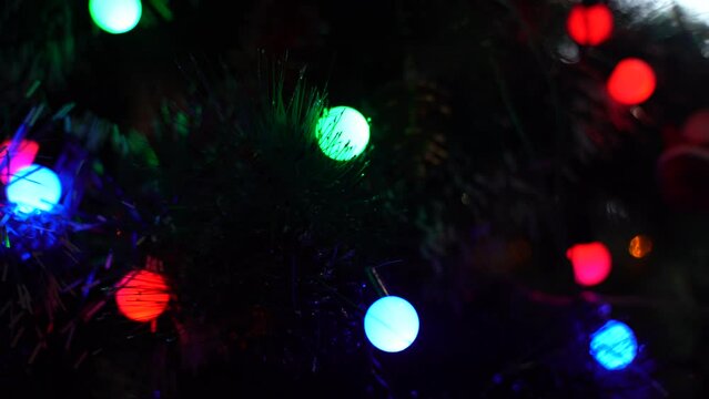Background image of a Christmas tree with a garland turned on in the evening. Close-up.