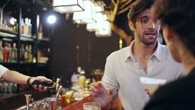 Caucasian man using mobile banking application on smartphone scan QR code for making online payment while hangout party at restaurant bar. Electronic banking and Contactless payment technology concept