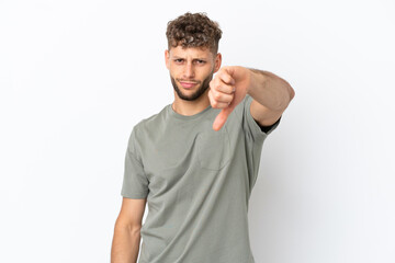 Young caucasian handsome man isolated on white background showing thumb down with negative...