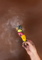 Womens hands holding a smoking smudge stick to banish bad energy. Dried herbs and flowers are tied into a bundle with a thread. Homemade incense stick for the practice of mindfulness meditation.