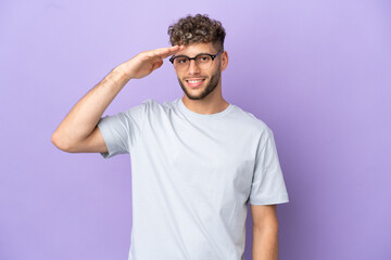 Obraz premium Delivery caucasian man isolated on purple background saluting with hand with happy expression