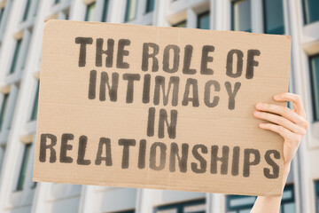 The phrase " The Role of Intimacy in Relationships " is on a banner in men's hands with blurred background. Sexual. Wife. Happiness. Looking. Lying. Role. Adult. Bed. Intimate. Two. Foreplay. Girl