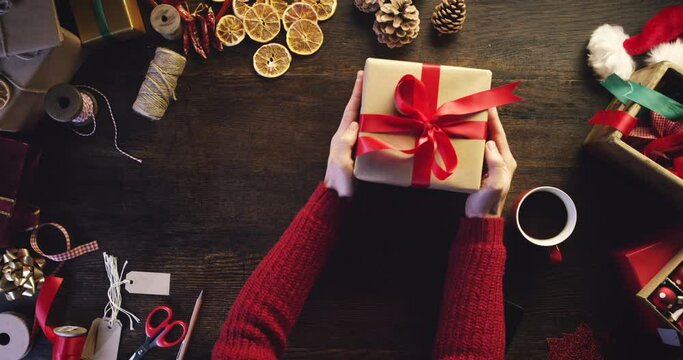 Top view, woman or hands wrapping christmas presents, writing gift card or drinking coffee at wooden house table in home living room. Person, festive box and xmas product for celebration event giving
