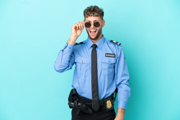 Fototapeta premium Young police blonde man isolated white on blue background with glasses and surprised
