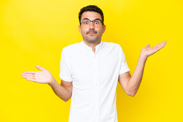 Young handsome man over isolated yellow background making doubts gesture