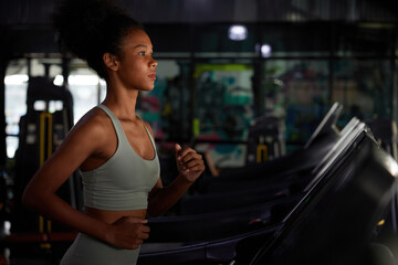 young sports woman working out and running on treadmill in gym