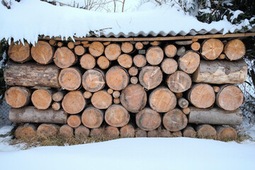 Firewood stacked in winter. Chopped stack of firewood under snow. Pile of Firewood. Preparation of...