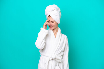 Young woman in a bathrobe isolated on blue background laughing