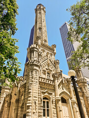 Fototapeta na wymiar Chicago, IL - May 17th, 2022: People pass by the Chicago Water Tower which remains one of the few structures to survive the Great Chicago Fire and is on the National Register of Historic Places.