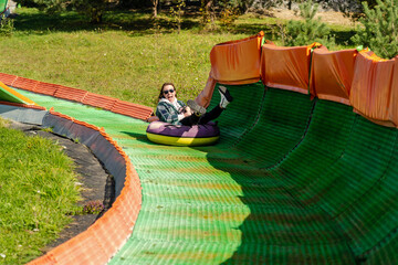 Happy woman rolling down the tubing track on a sunny day
