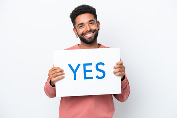 Young Brazilian man isolated on white background holding a placard with text YES with happy expression