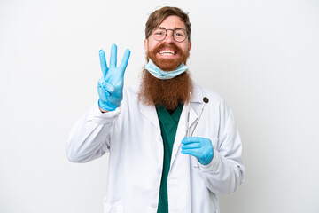 Dentist reddish man holding tools isolated on white background happy and counting three with fingers