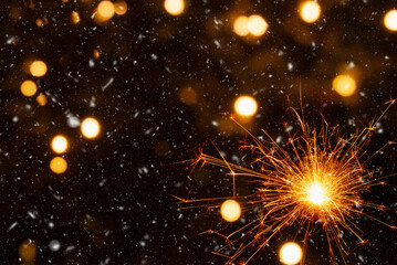 Burning sparkler on abstract snowy background, party concept