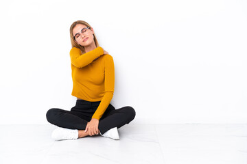 Fototapeta premium Blonde Uruguayan girl sitting on the floor suffering from pain in shoulder for having made an effort