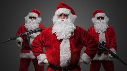 Portrait of isolated on gray background crew of three santa dressed in red costumes.