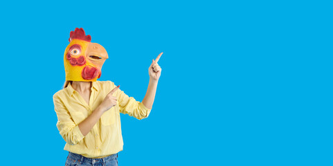 Creative and trends. Funny woman in rubber mask of chicken points to content copy space on light...