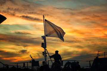 Waving flag of the russian navy on a warship of the baltic fleet against the backdrop of sunset