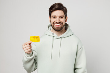 Young rich cheerful smiling happy caucasian man wear mint hoody look camera hold in hand mock up of...