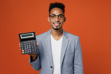 Young smart serious employee business man corporate lawyer wear classic formal grey suit shirt glasses work in office hold use blank screen calculator isolated on plain red orange background studio