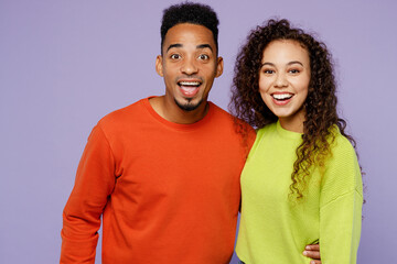 Young surprised excited couple two friends family man woman of African American ethnicity wear casual clothes together look camera with opened mouth isolated on pastel plain light purple background.