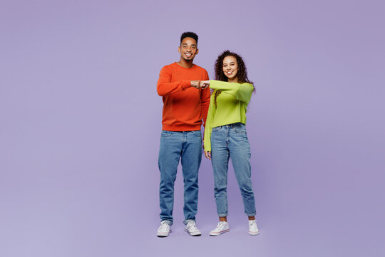 Full Body Young Happy Couple Two Friends Family Man Woman Of African American Ethnicity Wearing Casual Clothes Together Meet Each Other Give Fist Bump Isolated On Pastel Plain Light Purple Background.