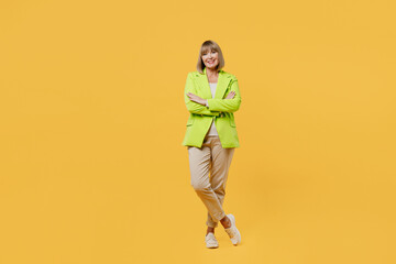 Fototapeta na wymiar Full body smiling fun elderly woman 50s year old wearing green jacket white t-shirt hold hands crossed folded look camera isolated on plain yellow background studio portrait. People lifestyle concept