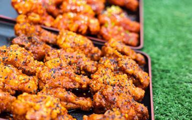 Close-up view of fried chicken drumsticks topped with black and white sesame seeds.