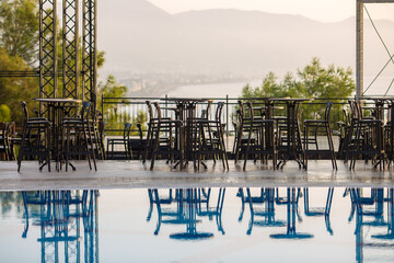 Empty tables and chairs near the open outdoor concert stage on the seashore.