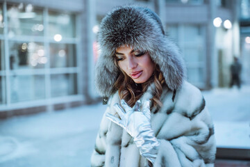 Woman in winter hat and fur coat. It's winter outside, it's snowing. Winter, Christmas and New Year...