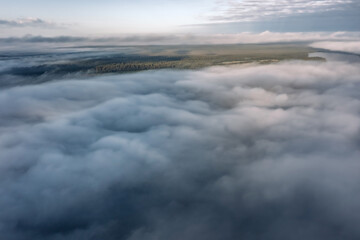 Obraz premium Aerial view of dense pine forest, field and lake covered with ribbons of low fog, Karelia, Russia