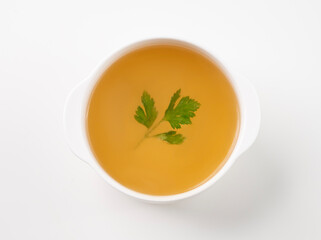 Meat broth with parsley in a white plate on a isolated background. The concept of healthy diet food.