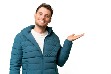 Brazilian man over isolated chroma key background holding copyspace imaginary on the palm to insert an ad